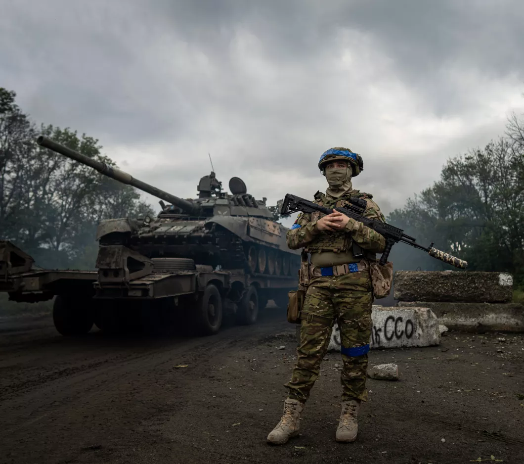 A solder standing in front of a tank