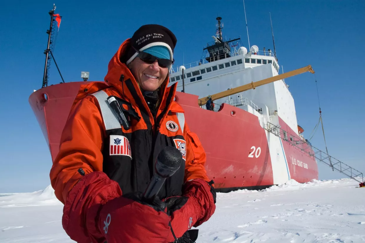 Elizabeth Aronld stands on the sea ice in front of a Russian icebreaker. 