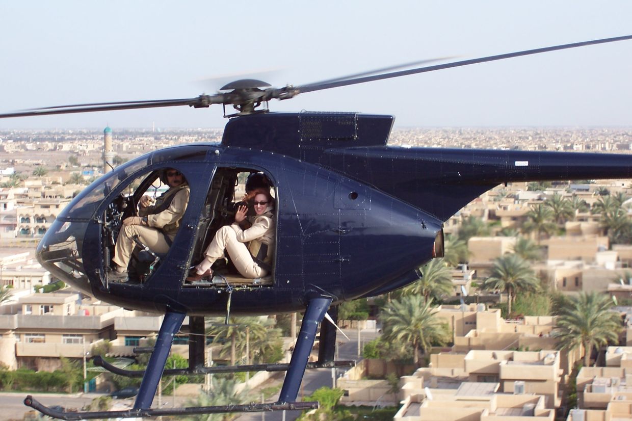 Meghan O'Sullivan waves from the open door of a small helicopter flying over Iraq.