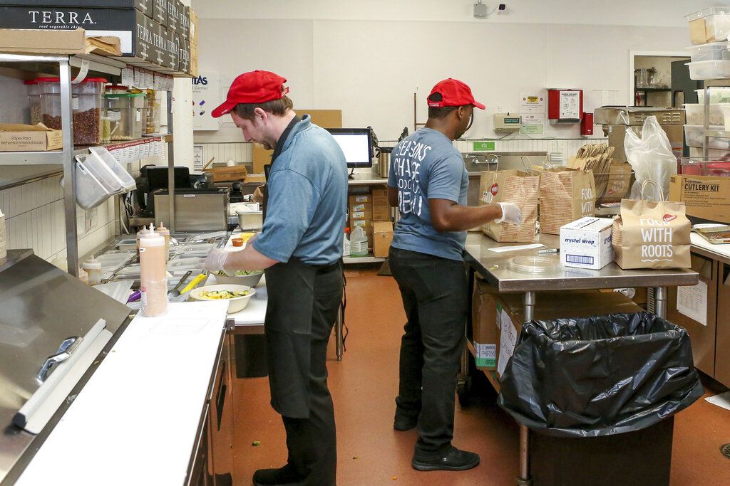 William Burns, left, general manager of the B.Good ghost kitchen inside Kitchen United's Chicago, Ill., location prepares food for delivery.