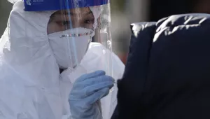 A medical worker wearing protective gear takes samples from a woman during a COVID-19 testing at a coronavirus testing site in Seoul, South Korea on Dec. 12, 2020.