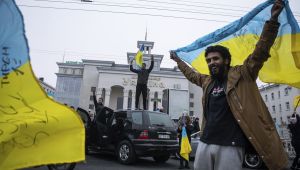 A man celebrates holding a Ukrainian flag over his head.