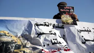 An Arab Israeli man holds a banner in front of Israel's parliament during a protest against the demolition of homes without proper permits by Israeli authorities and the killing of an Israeli Arab man after he rammed his vehicle into a group of police officers killing one of them in Jerusalem, Monday, Jan. 23, 2017. (AP Photo/Ariel Schalit)