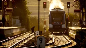 A man runs over rails to reach a regional hydrogen train in the station of Wehrheim, near Frankfurt, Germany, early Monday, Aug. 26, 2024.