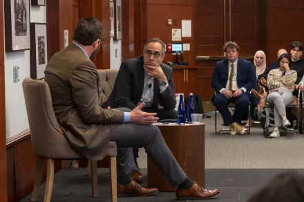 Tarek Masoud intently listens to a guest on stage.