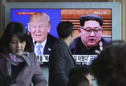 Photo of a man watching a screen in Seoul that shows photos of Donald Trump and Kim Jong-un.