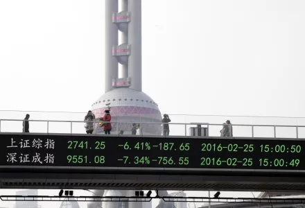 Photo of people crossing bridge in Shanghai that shows stock prices.