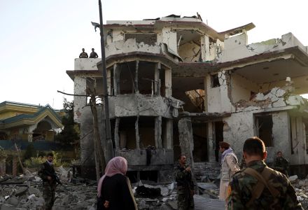 Afghan security personnel inspect a damaged building