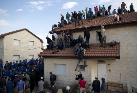 Settlers climb on a roof as Israeli police are evicting them the West Bank settlement of Ofra