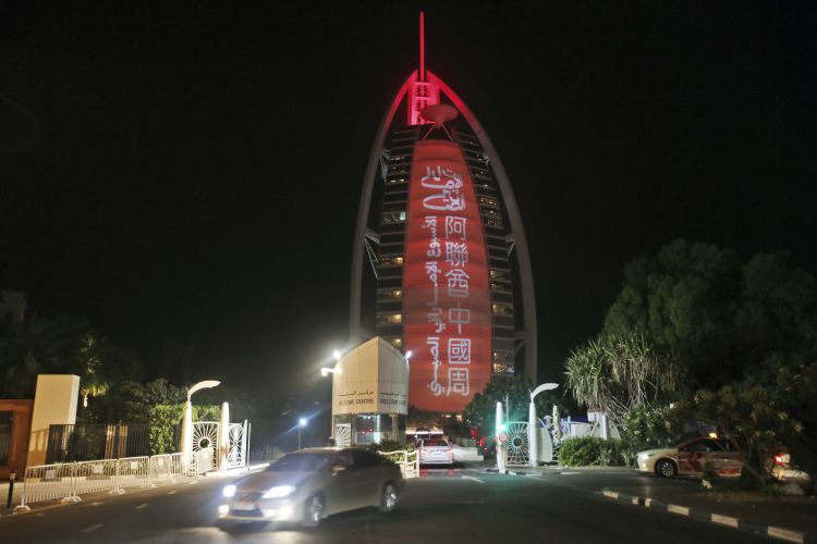 In this Wednesday, July 18, 2018 photo, a sign reading "UAE Chinese Week" in Chinese and Arabic is projected onto the Bus Al Arab luxury hotel to celebrate the UAE Chinese Week in Dubai, United Arab Emirates. Chinese President Xi Jinping is heading to Abu Dhabi in his first trip to the United Arab Emirates as the leader of China as the two countries look to strengthen trade ties and expand investment.